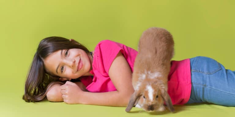 A girl laying on the floor with a rabbit.